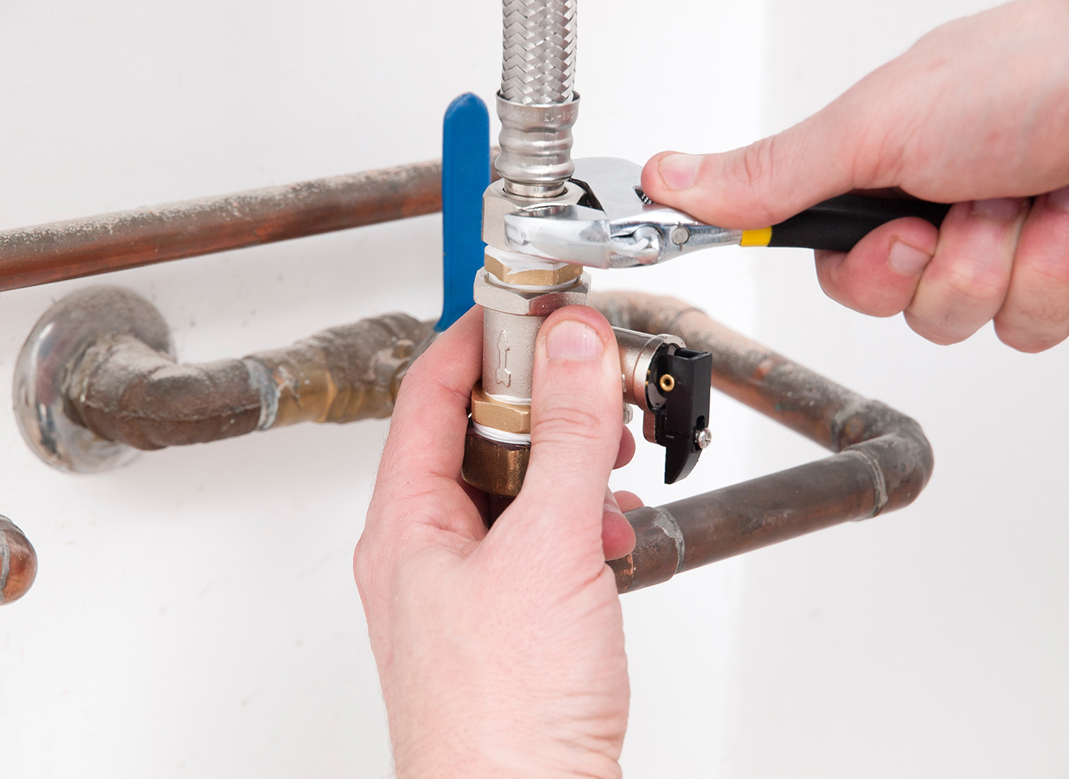 Hands repairing the plumbing pipes of an electric boiler with a spanner